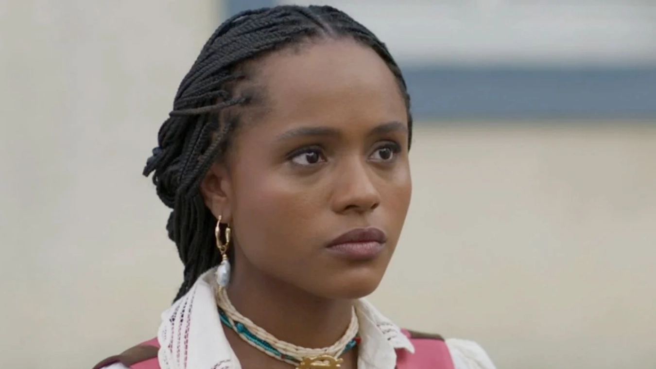 Alika (lucia) com tranças e expressão séria.